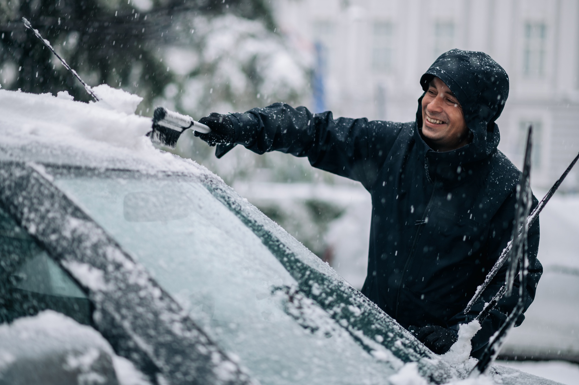 Middle aged man cleaning car from snow and ice